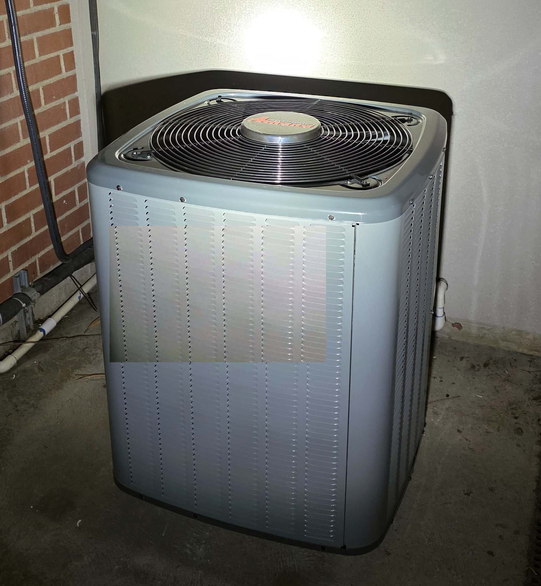 Close-up of outdoor AC condenser at brick exterior